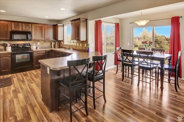 2118 W Foxwood St, West Haven, UT 84401 - kitchen with black appliances, a sink, wood finished floors, a kitchen breakfast bar, and tasteful backsplash