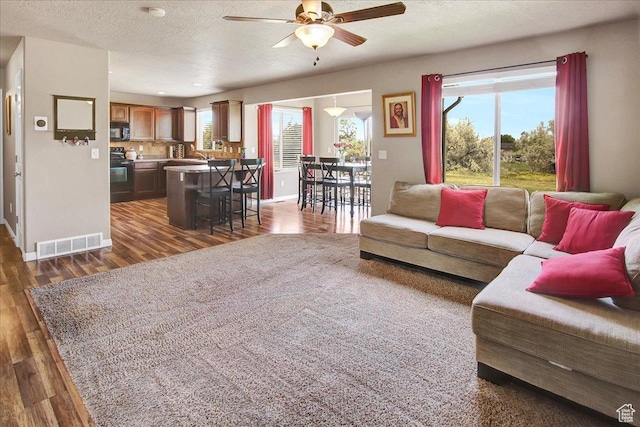 2118 W Foxwood St, West Haven, UT 84401 - living room with ceiling fan, dark wood-style floors, plenty of natural light, baseboards, and a textured ceiling