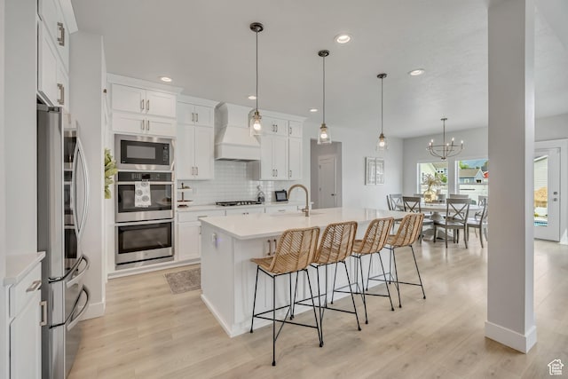 207 S Summer Breeze Ln, Layton, UT 84041 - kitchen featuring custom exhaust hood, a breakfast bar area, light countertops, tasteful backsplash, and light wood-style floors