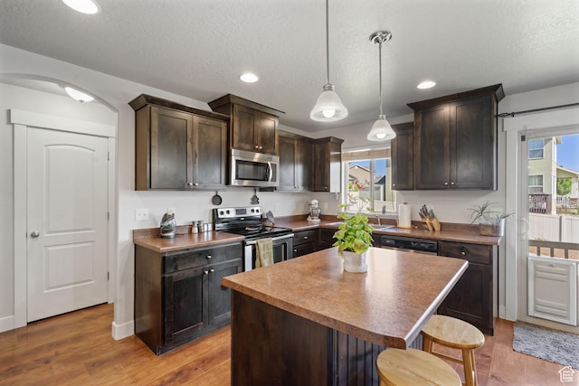 78 W Wildflower Dr, Saratoga Springs, UT 84045 - kitchen featuring appliances with stainless steel finishes, dark brown cabinetry, a breakfast bar area, wood finished floors, and healthy amount of natural light