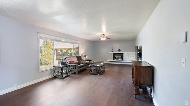 143 E 100 N, Gunnison, UT 84634 - living area featuring ceiling fan, a glass covered fireplace, dark wood-style flooring, a textured ceiling, and baseboards