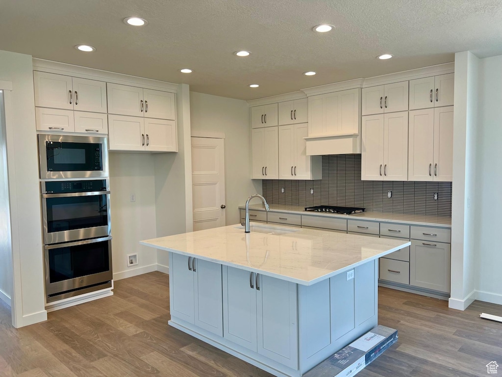 11129 S Bingham Rim Rd W Unit 5-426, South Jordan, UT 84009 - kitchen featuring appliances with stainless steel finishes, wood finished floors, white cabinetry, tasteful backsplash, and recessed lighting