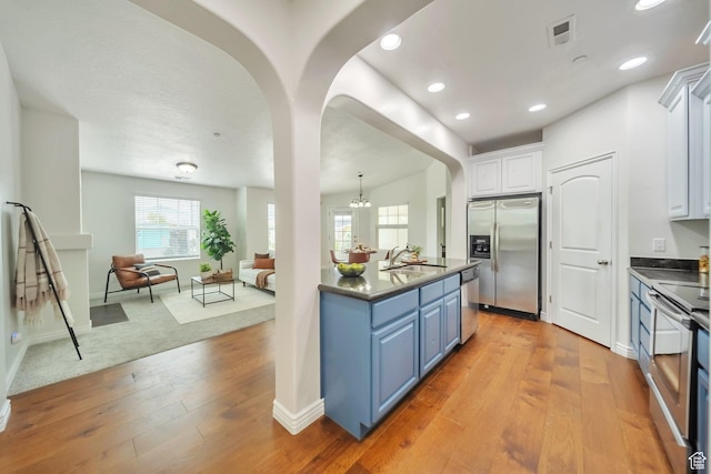 11738 S Currant Dr Unit 112, South Jordan, UT 84009 - kitchen with stainless steel appliances, blue cabinetry, open floor plan, dark countertops, and white cabinets