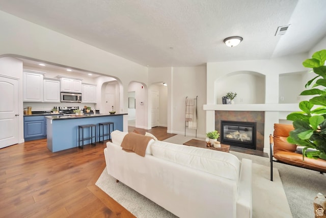 11738 S Currant Dr Unit 112, South Jordan, UT 84009 - living area with a fireplace, wood finished floors, arched walkways, recessed lighting, and a textured ceiling
