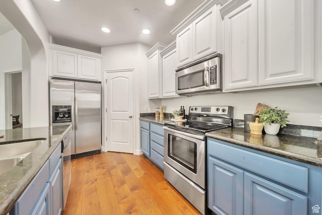 11738 S Currant Dr Unit 112, South Jordan, UT 84009 - kitchen featuring stainless steel appliances, blue cabinetry, white cabinetry, arched walkways, and recessed lighting