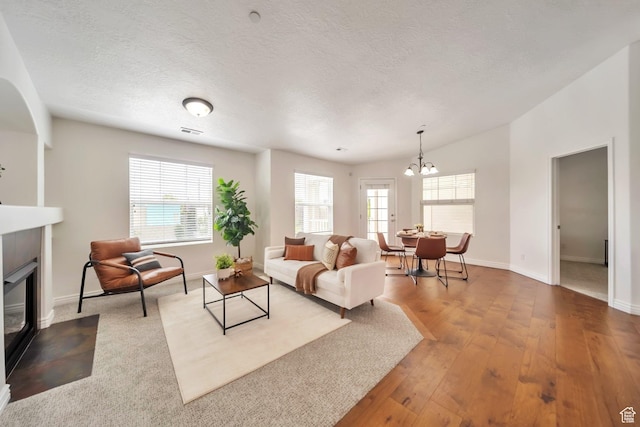 11738 S Currant Dr Unit 112, South Jordan, UT 84009 - living area with a fireplace with flush hearth, a chandelier, baseboards, wood finished floors, and a textured ceiling