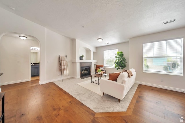 11738 S Currant Dr Unit 112, South Jordan, UT 84009 - living room with hardwood / wood-style floors, arched walkways, a tiled fireplace, baseboards, and a textured ceiling
