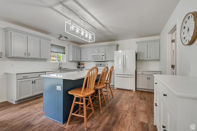 856 S 1580 W, Lehi, UT 84043 - kitchen featuring white appliances, gray cabinetry, tasteful backsplash, a breakfast bar, and dark wood-type flooring