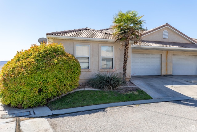 2056 E Middleton Clb, St George, UT 84770 - view of front facade with a garage, driveway, stucco siding, and a tiled roof