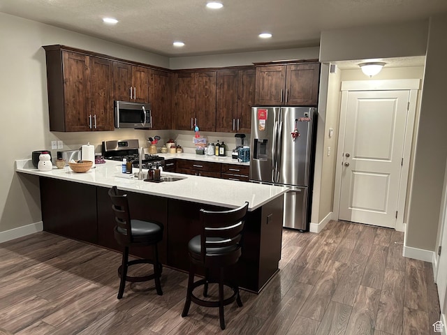 9681 S Zakro Ln, South Jordan, UT 84095 - kitchen featuring stainless steel appliances, dark brown cabinetry, dark wood-style flooring, a peninsula, and recessed lighting