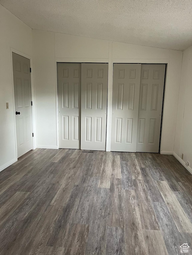 380 W Main, Myton, UT 84052 - unfurnished bedroom with wood finished floors, a textured ceiling, and multiple closets