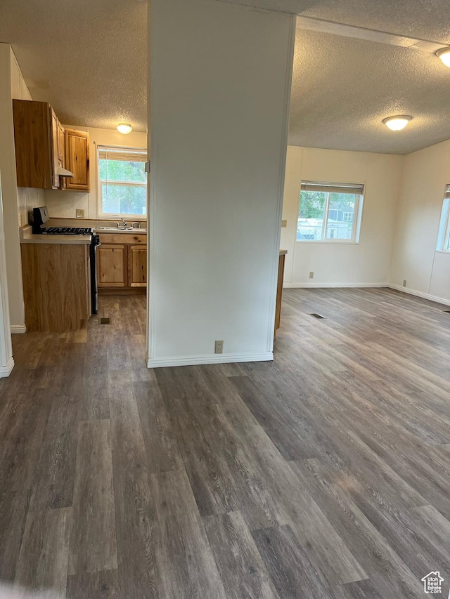 380 W Main, Myton, UT 84052 - kitchen with open floor plan, a textured ceiling, range, brown cabinetry, and healthy amount of natural light