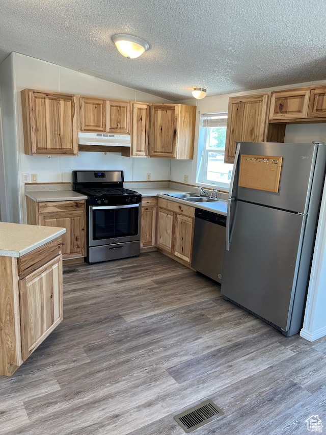 380 W Main, Myton, UT 84052 - kitchen with appliances with stainless steel finishes, under cabinet range hood, light countertops, a textured ceiling, and wood finished floors