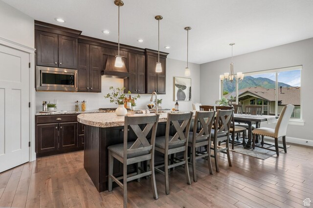 6035 Hidden Valley Rd, Mountain Green, UT 84050 - kitchen featuring stainless steel microwave, dark brown cabinets, light wood-style flooring, and recessed lighting
