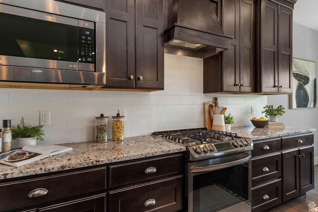 6035 Hidden Valley Rd, Mountain Green, UT 84050 - kitchen with stainless steel appliances, custom exhaust hood, dark brown cabinetry, and light stone countertops