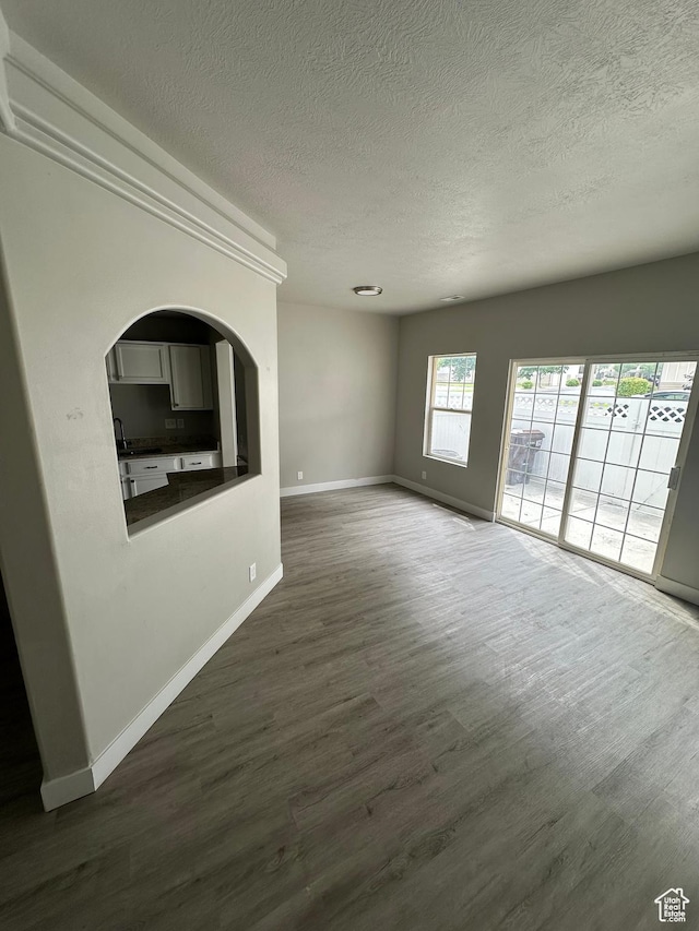 39 W 1930 N, Tooele, UT 84074 - unfurnished living room with a textured ceiling, baseboards, dark wood-style floors, and arched walkways