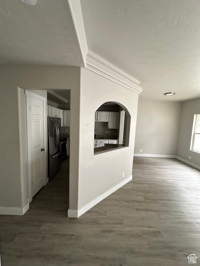 39 W 1930 N, Tooele, UT 84074 - unfurnished living room featuring a textured ceiling, dark wood-style flooring, baseboards, a sink, and arched walkways