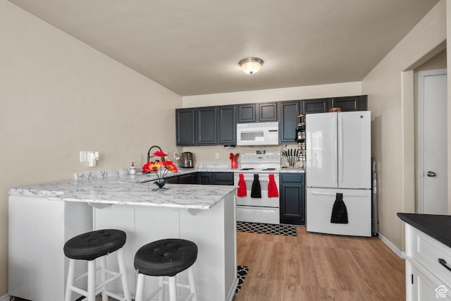 1722 N 80 E, Tooele, UT 84074 - kitchen with white appliances, a peninsula, a breakfast bar area, light wood-style floors, and light stone counters