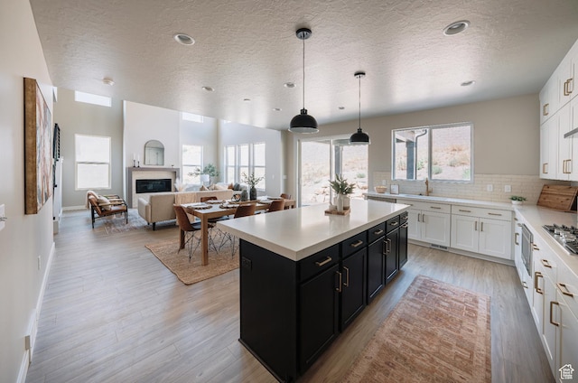 1651 W Canyon Rim Rd Unit 633, Lehi, UT 84043 - kitchen featuring dark cabinetry, a center island, a textured ceiling, white cabinetry, and light countertops