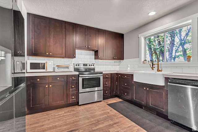 850 E 760 N, Lehi, UT 84043 - kitchen with appliances with stainless steel finishes, a sink, backsplash, light wood-style flooring, and a textured ceiling