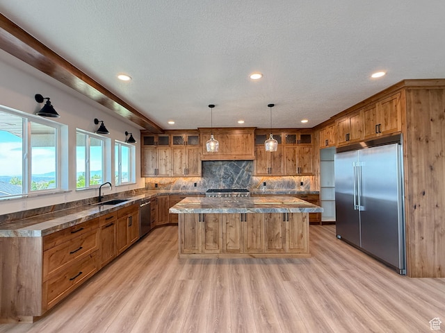 1141 E 4100 N, North Ogden, UT 84414 - kitchen featuring appliances with stainless steel finishes, a kitchen island, brown cabinets, a sink, and light wood finished floors