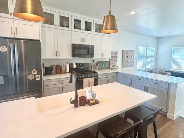 953 N 850 E Unit 229, Layton, UT 84041 - kitchen featuring appliances with stainless steel finishes, a peninsula, light countertops, wood finished floors, and glass insert cabinets