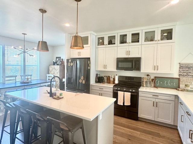 953 N 850 E Unit 229, Layton, UT 84041 - kitchen with black appliances, wood finished floors, light countertops, a breakfast bar, and white cabinetry