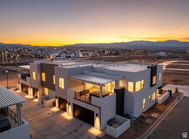 712 W Coastline Pl, St George, UT 84790 - back of house at dusk with stucco siding, an attached garage, a balcony, and a mountain view