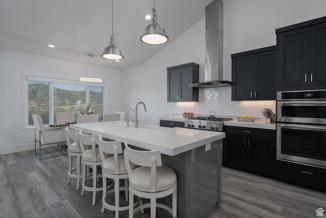 11103 N Shoreline Dr Unit # 3, Hideout, UT 84036 - kitchen with wall chimney range hood, stainless steel appliances, light countertops, dark cabinetry, and a breakfast bar area