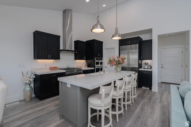 11103 N Shoreline Dr Unit # 3, Hideout, UT 84036 - kitchen with wall chimney exhaust hood, dark cabinetry, stainless steel appliances, light countertops, and a breakfast bar