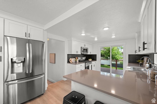2524 E Redondo Ave, Salt Lake City, UT 84108 - kitchen with appliances with stainless steel finishes, a peninsula, a sink, white cabinetry, and a textured ceiling