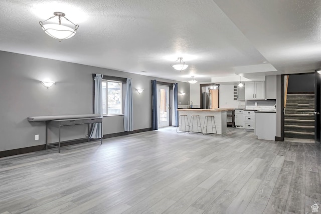 2101 W 325 S, Mapleton, UT 84664 - unfurnished living room featuring a textured ceiling, light wood-style floors, and stairs