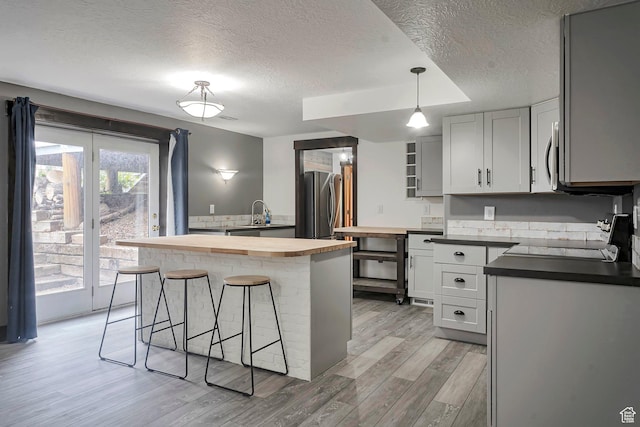2101 W 325 S, Mapleton, UT 84664 - kitchen featuring butcher block countertops, appliances with stainless steel finishes, a textured ceiling, a kitchen bar, and light wood-type flooring