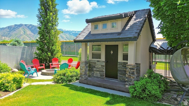 674 S 150 W, Hyde Park, UT 84318 - rear view of property featuring a mountain view, a fire pit, stucco siding, stone siding, and an outdoor structure