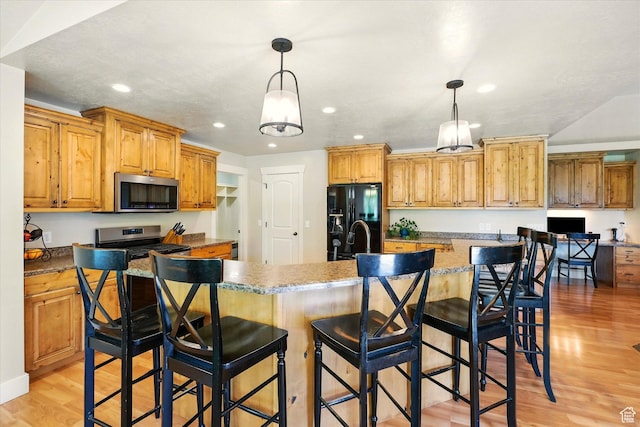 674 S 150 W, Hyde Park, UT 84318 - kitchen featuring appliances with stainless steel finishes, light wood-type flooring, recessed lighting, decorative light fixtures, and a center island with sink