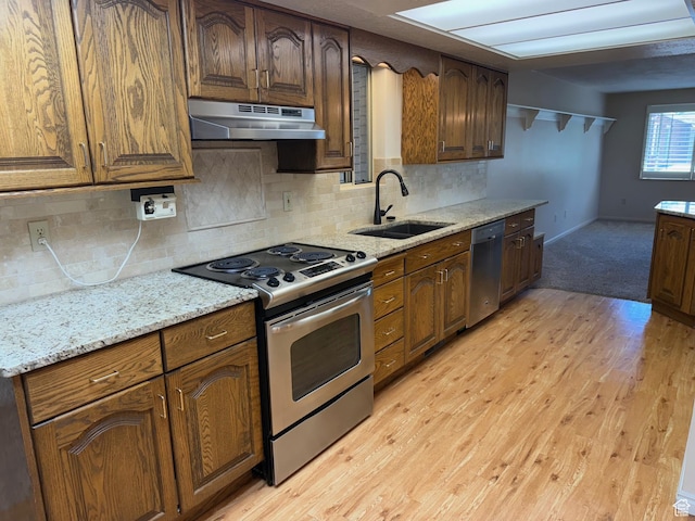 5253 S 2150 W, Roy, UT 84067 - kitchen with appliances with stainless steel finishes, under cabinet range hood, a sink, light wood-style floors, and backsplash