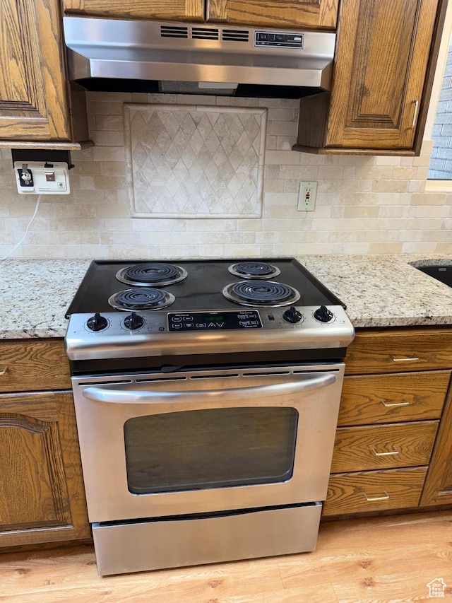 5253 S 2150 W, Roy, UT 84067 - kitchen featuring stainless steel range with electric cooktop, under cabinet range hood, brown cabinetry, tasteful backsplash, and light stone counters