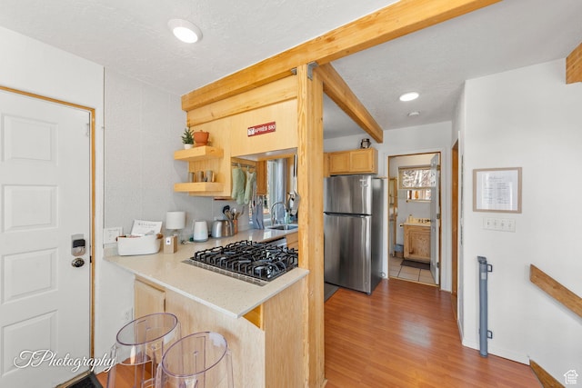 332 W Pinehurst Dr, Brian Head, UT 84719 - kitchen with stainless steel appliances, a sink, light countertops, light brown cabinetry, and light wood-style floors