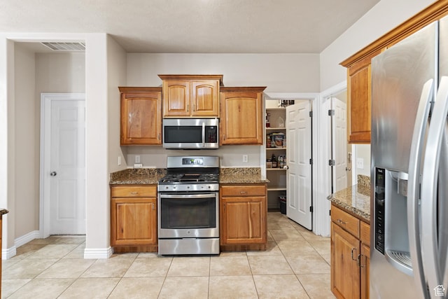 1500 E Mesa View Ln, Washington, UT 84780 - kitchen featuring stainless steel appliances, stone countertops, brown cabinets, and light tile patterned floors