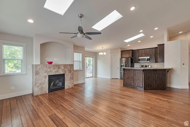 222 E 905 N, Orem, UT 84057 - unfurnished living room featuring a skylight, a tiled fireplace, light wood-style flooring, baseboards, and lofted ceiling
