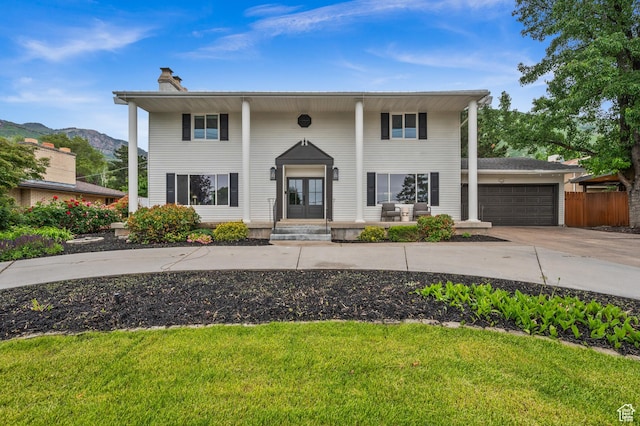 7585 S 3500 E, Salt Lake City, UT 84121 - greek revival house featuring a chimney, concrete driveway, a garage, french doors, and a mountain view