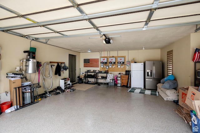 2908 W Bison Ridge Rd, South Jordan, UT 84095 - garage featuring stainless steel fridge with ice dispenser, freestanding refrigerator, a garage door opener, and a central vacuum unit
