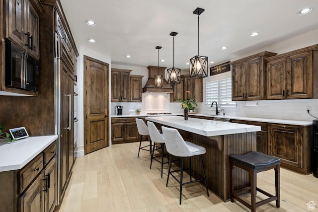 2908 W Bison Ridge Rd, South Jordan, UT 84095 - kitchen featuring a sink, black microwave, a kitchen island, light wood-type flooring, and a kitchen bar