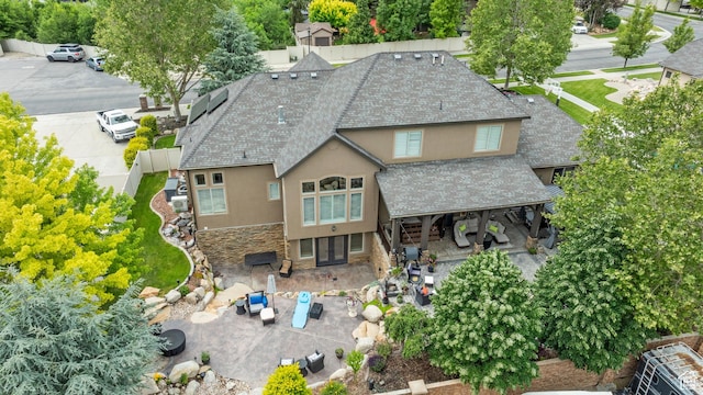 2908 W Bison Ridge Rd, South Jordan, UT 84095 - rear view of property featuring a shingled roof, stucco siding, french doors, stone siding, and a patio