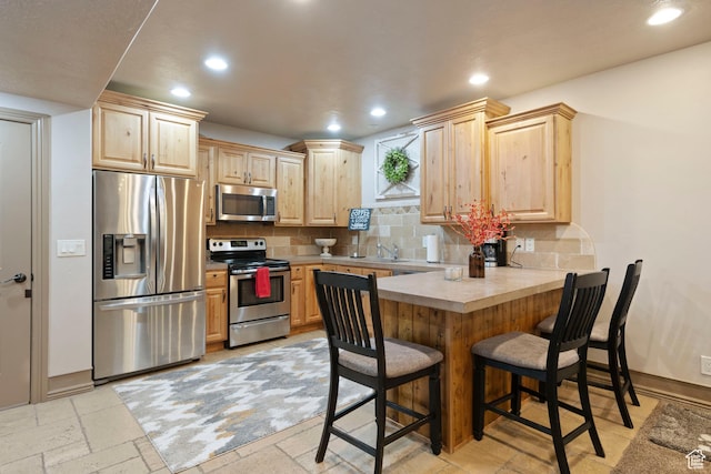 2908 W Bison Ridge Rd, South Jordan, UT 84095 - kitchen with appliances with stainless steel finishes, light brown cabinets, a peninsula, recessed lighting, and a kitchen breakfast bar
