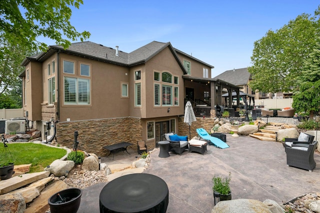 2908 W Bison Ridge Rd, South Jordan, UT 84095 - back of house with stucco siding, a patio, stone siding, an outdoor living space with a fire pit, and a cooling unit