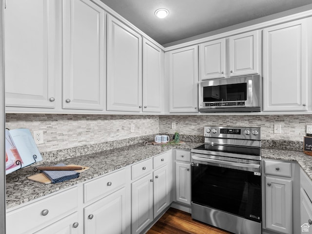 6749 N 2200 W Unit B-303, Park City, UT 84098 - kitchen with stainless steel appliances, tasteful backsplash, white cabinetry, light stone counters, and dark wood-style floors