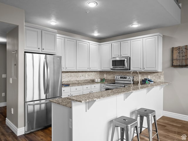 6749 N 2200 W Unit B-303, Park City, UT 84098 - kitchen with appliances with stainless steel finishes, a peninsula, baseboards, a kitchen breakfast bar, and recessed lighting