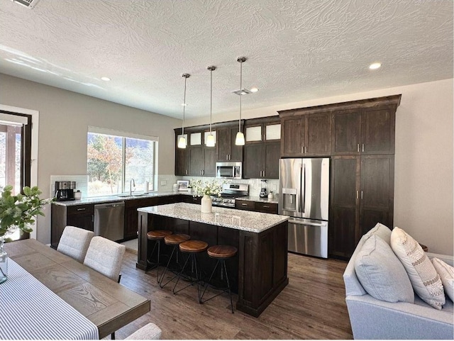 108 Trapper Cir Unit A, Springdale, UT 84767 - kitchen featuring stainless steel appliances, dark brown cabinets, a center island, a kitchen breakfast bar, and tasteful backsplash