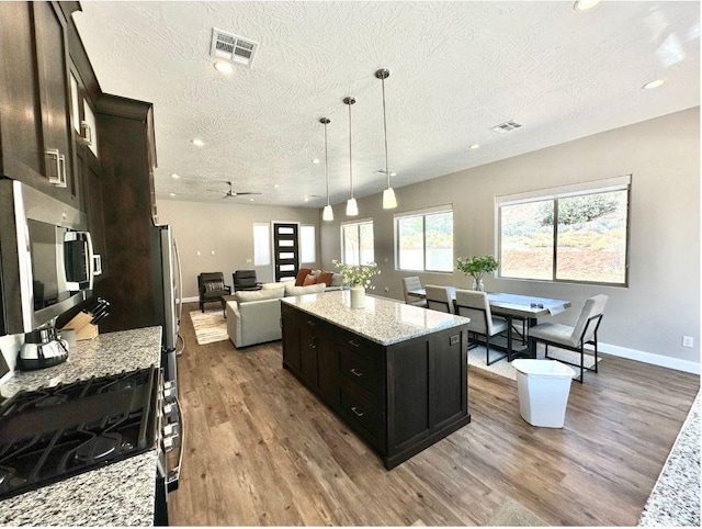 108 Trapper Cir Unit A, Springdale, UT 84767 - kitchen featuring appliances with stainless steel finishes, a textured ceiling, wood finished floors, open floor plan, and a kitchen island